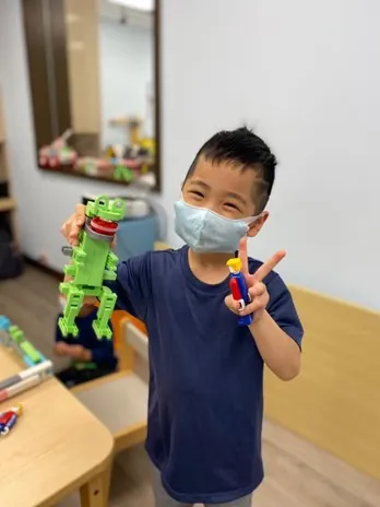 孩子舉起恐龍造型 LASY 模型,開心比 V